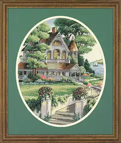 Готова вишита картина за набором Dimensions 03874 "Lovely Victorian Home" (Чудовий вікторіанський будинок). Класичний світлий маєток із башточкою та затишною верандою, що потопає у зелені квітучого літнього саду, вишитий технікою лічильного хреста на канві Aida 14. Сюжет оформлено в овальне зелене паспарту та дерев'яну раму, на задньому плані видніється спокійне озеро з вітрильником.