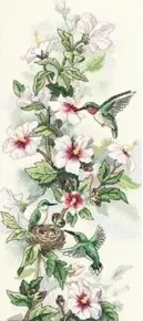 Готова вертикальна вишита картина за набором Dimensions 13667 "Hummingbird Art" (Мистецтво з Колібрі). На витонченій гілці з біло-рожевими квітами та зеленим листям літають три маленькі смарагдові пташки колібрі біля затишного гнізда з яєчками. Робота вишита технікою лічильного хреста на світлій канві Aida 14 з ефектом ніжного акварельного фону