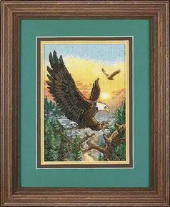 Готова вишита картина хрестиком за набором Dimensions 06759 "Eagles" (Орли). На малюнку зображений могутній білоголовий орлан, що спускається на гілку старого дерева на тлі хвойного лісу та золотого заходу сонця. Робота виконана технікою лічильного хреста на світло-блакитній канві Aida 18.