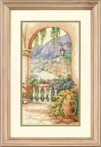 Готова вишита картина хрестиком за набором Dimensions 35219 "Terrace Arch" (Арка на терасі). Вид крізь старовинну кам'яну арку на сонячну середземноморську терасу з квітами у горщиках, кованим ліхтарем та балюстрадою. На задньому плані видніється морська бухта, гори та прибережне містечко, виконані у ніжній акварельній техніці. Робота вишита на канві Aida 14 кольору слонової кістки.