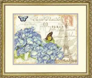отова вишита картина за набором Dimensions 70-35307 "Paris Hydrangea" (Паризька гортензія). На передньому плані пишні блакитні суцвіття гортензії та метелики на фоні вінтажної поштової листівки із зображенням Ейфелевої вежі та французькими каліграфічними написами. Робота вишита на канві Aida 14 кольору слонової кістки.