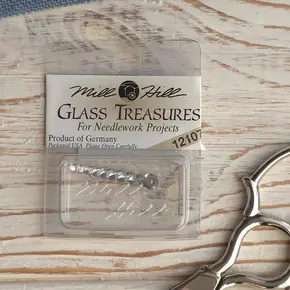 Оригінальна упаковка скляної прикраси для вишивки Mill Hill Glass Treasures 12107 Бурулька (Icicle foiled) на дерев'яному фоні — купити матеріали для рукоділля в Crazy Cross Stitch.